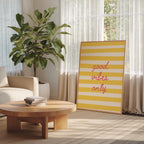 a living room with a large potted plant, a wooden coffee table, and a framed sign with the text "good vibes only" in a yellow and white striped design.
