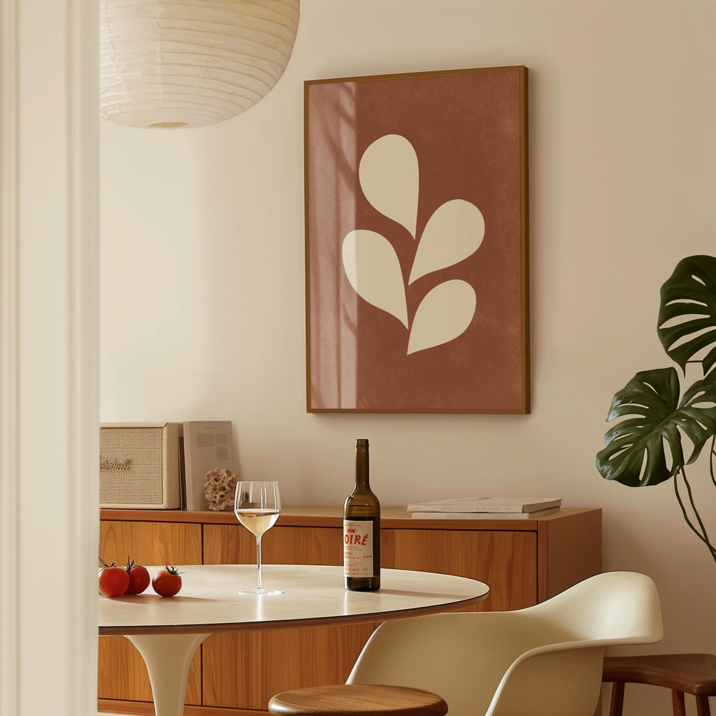 a dining room with a table set for two, a bottle of wine, and a framed leaf-shaped artwork on the wall.