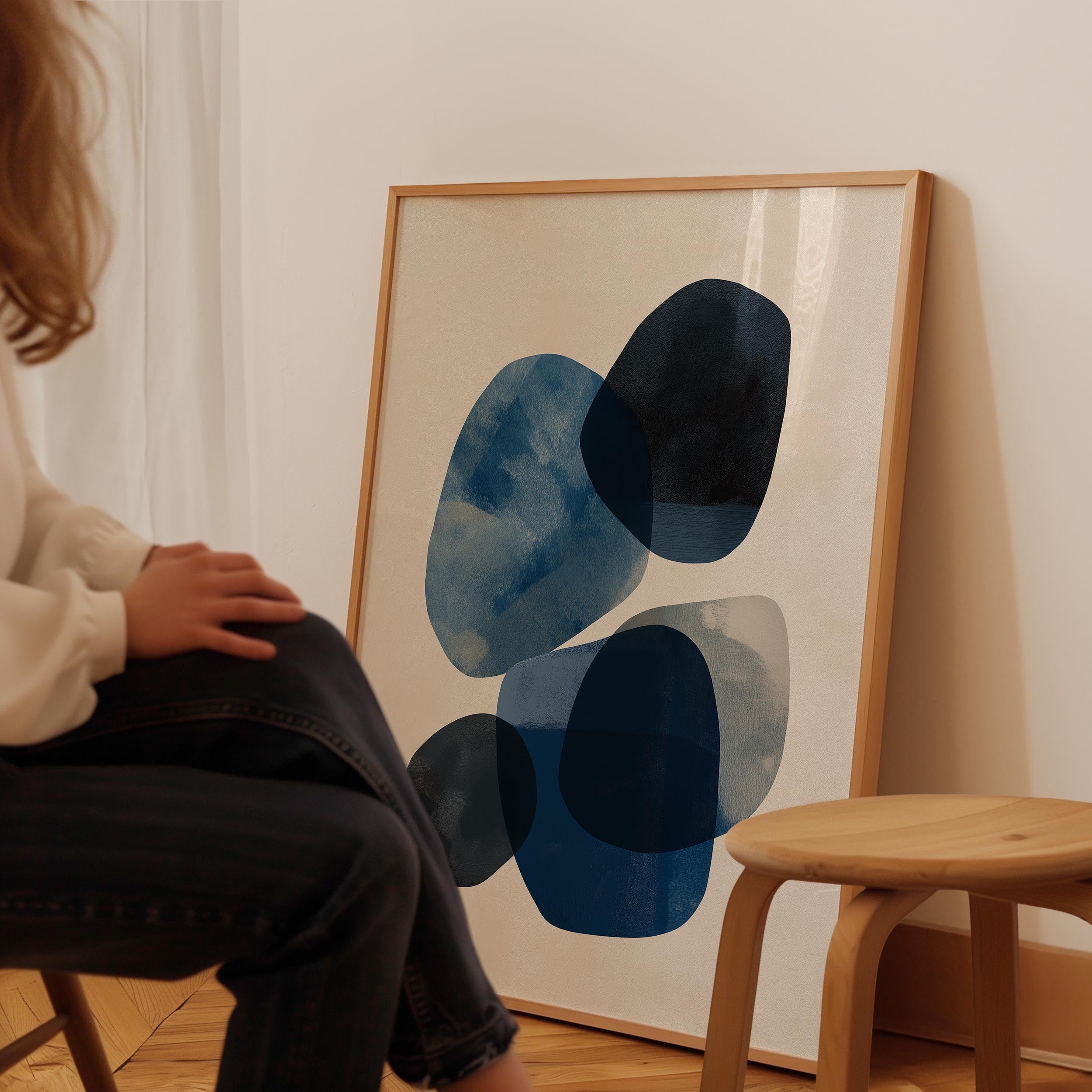 A person is sitting in a chair in front of a large abstract painting on a wall.