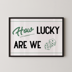 A framed poster with the text "How LUCKY ARE WE" and two dice graphics.