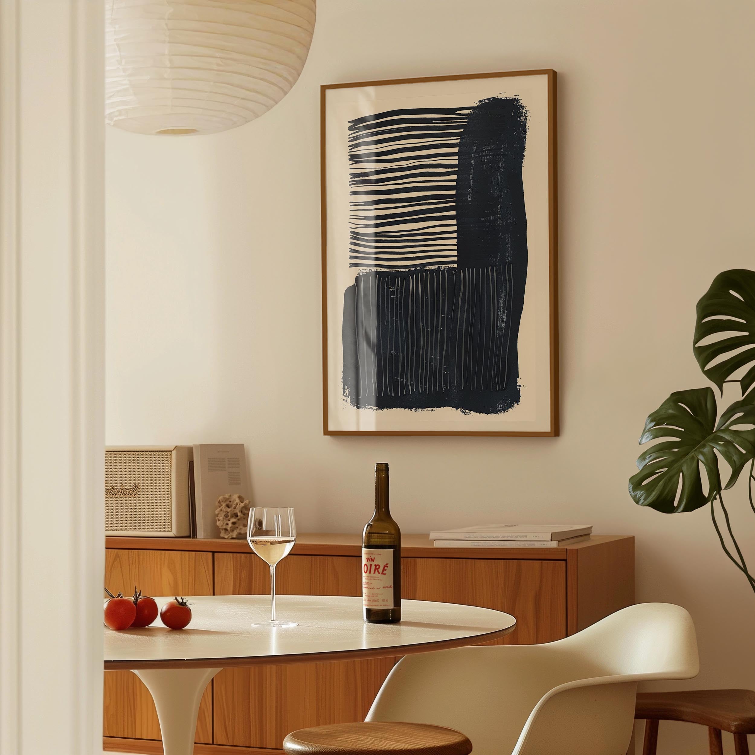 a dining area with a table, a bottle of wine, and a framed abstract painting on the wall.