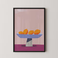A framed illustration of a bowl containing three oranges on a pink background.