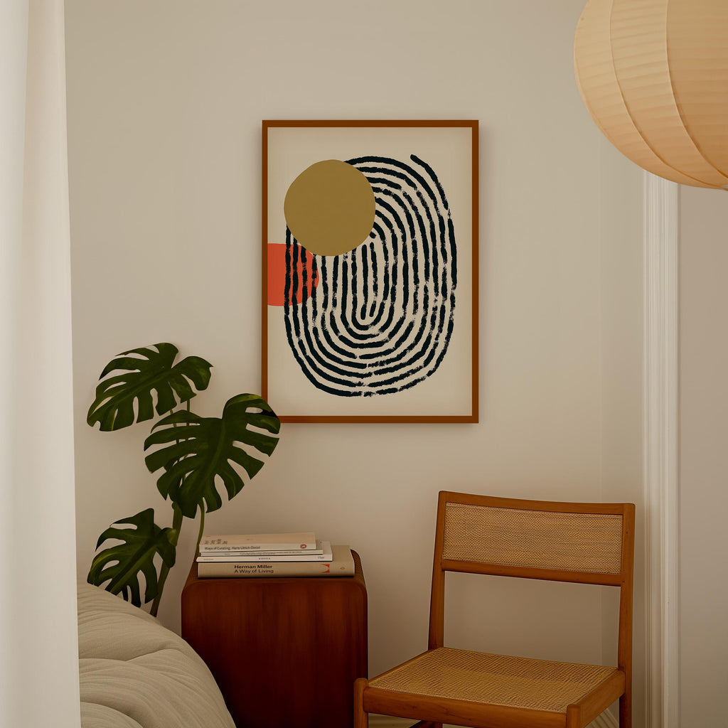 a minimalist living space with a framed abstract artwork hanging on the wall, a wooden chair, a stack of books, and a potted plant.