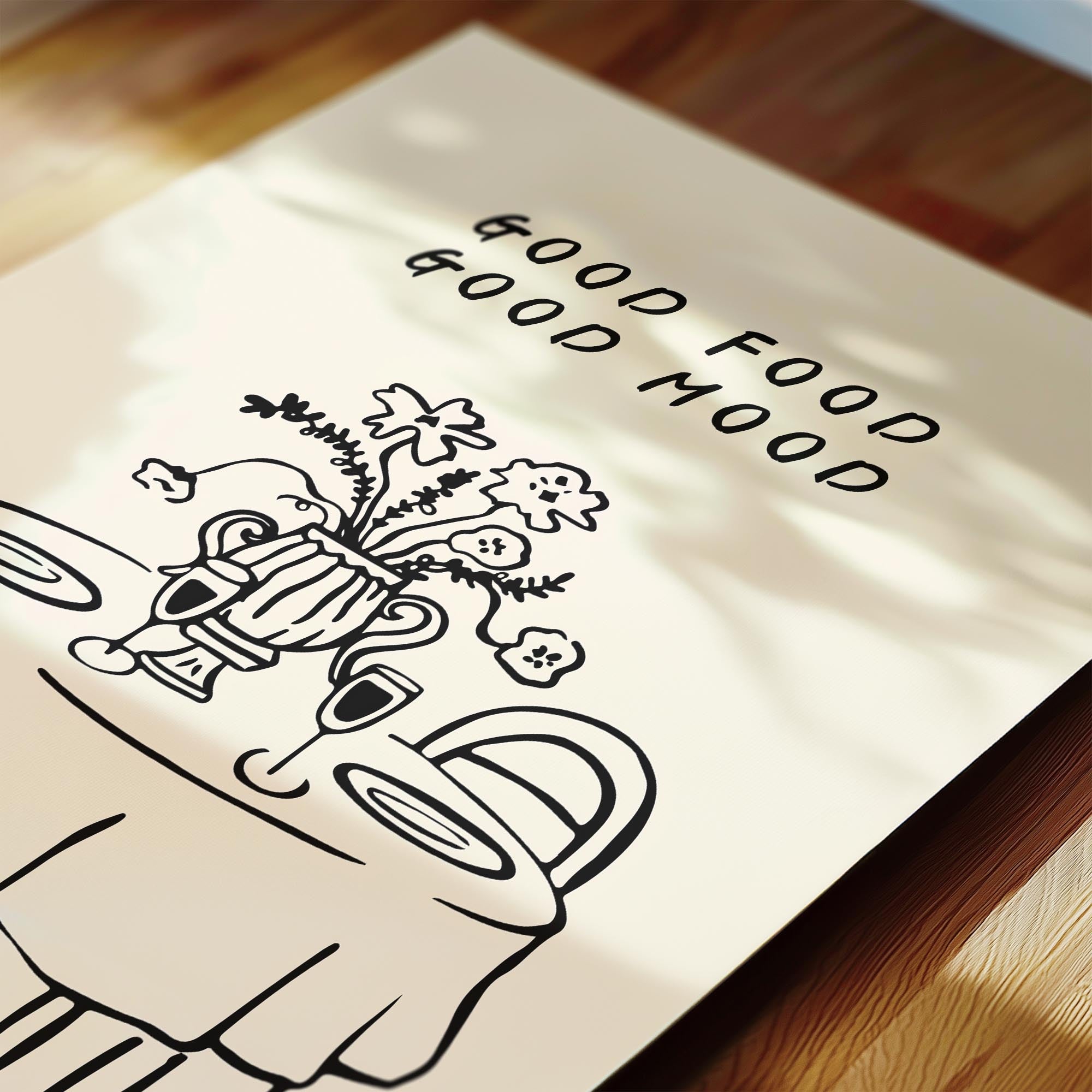 a close-up view of a white paper with a black and white illustration of a table with a vase of flowers and a wine glass. The text "GOOD FOOD GOOD MOOD" is written above the illustration.