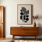 a modern interior design with a wooden cabinet, a framed abstract artwork, and a vase with dried flowers on a table.