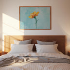a cozy bedroom scene with a wooden headboard and a framed painting of a yellow flower hanging above it.