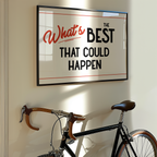 a framed motivational quote that says "What's BEST THAT COULD HAPPEN" on a wall, with a bicycle leaning against the wall below it.