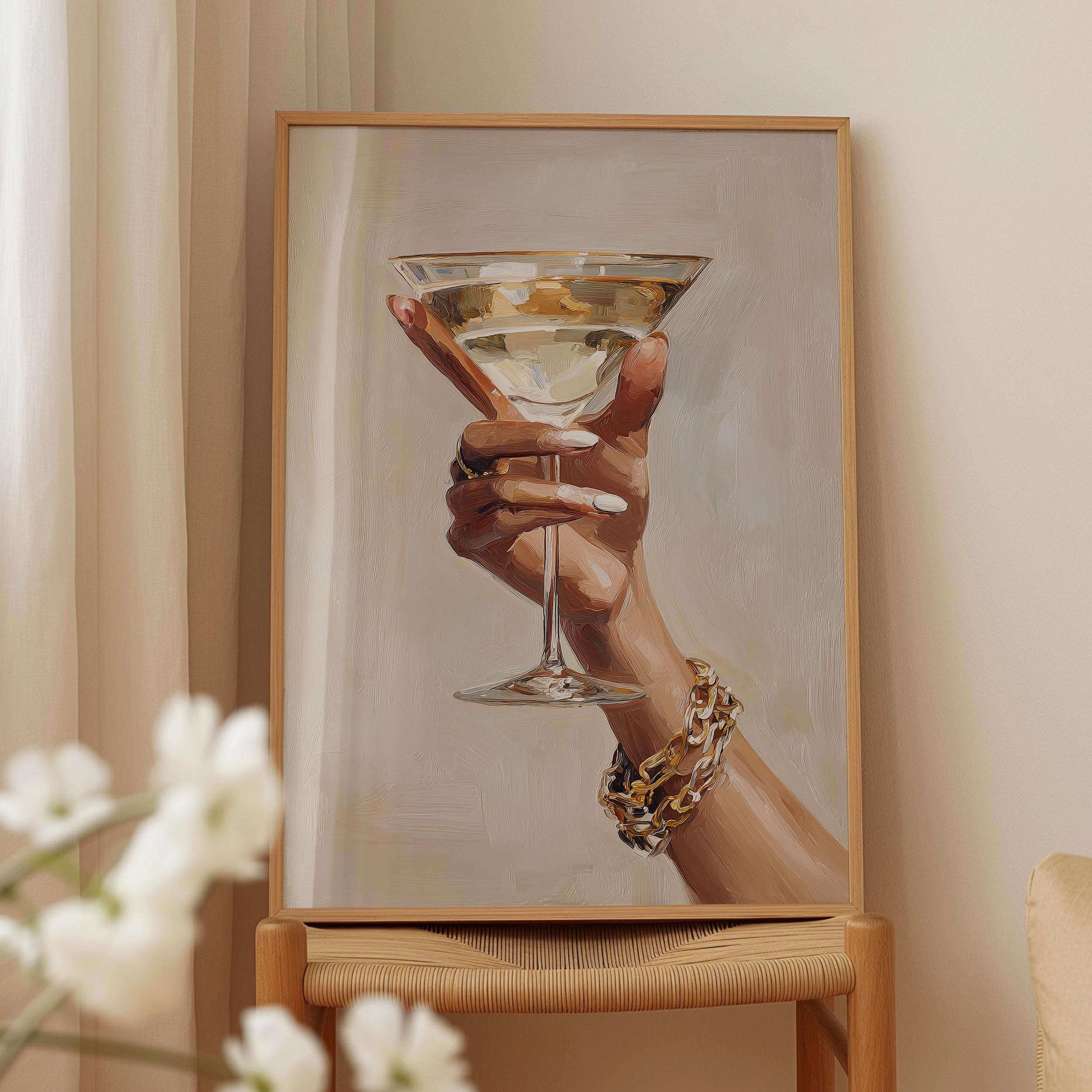 A framed painting of a hand holding a martini glass, with a bracelet on the wrist.