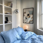 a cozy bedroom with a large bed, a framed picture of a cat on the wall, and a lamp on a nightstand.