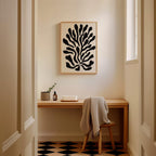 a cozy corner of a room with a wooden desk, a chair, and a framed abstract art piece hanging on the wall.