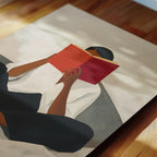 A person is sitting on a couch and reading a red book.