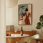 a dining area with a table set for two, a bottle of wine, and a framed painting of a woman in a red polka dot dress.
