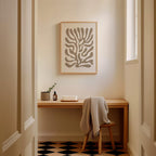 a cozy corner of a room with a wooden desk, a framed abstract artwork on the wall, and a chair with a blanket draped over it.