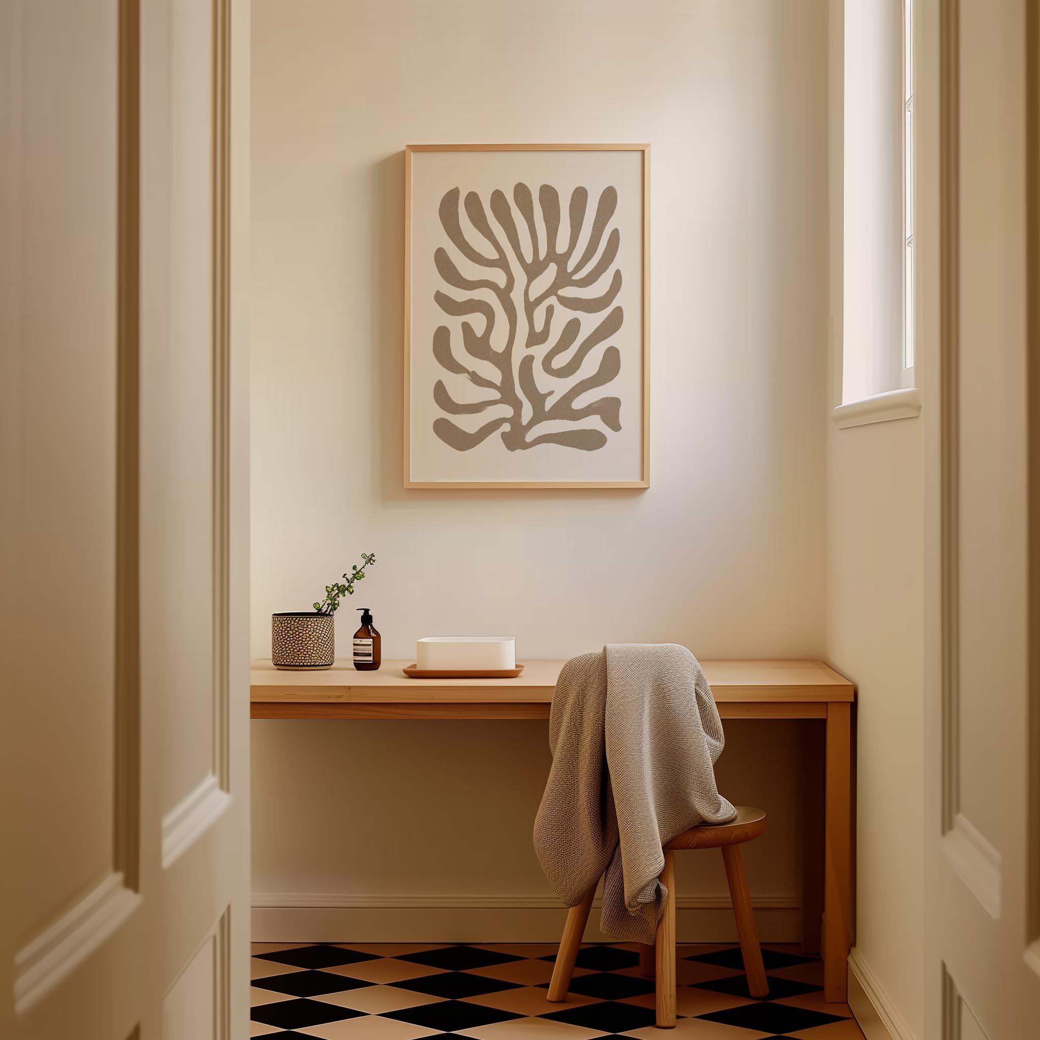 a cozy corner of a room with a wooden desk, a framed abstract artwork on the wall, and a chair with a blanket draped over it.