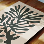 a close-up view of a piece of art with a stylized plant or leaf design in shades of green and pink.