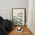 a cozy corner with a framed illustration of a hand pouring coffee into two cups, a white mug, and a book on a wooden floor.