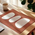 a wooden table with a red and white geometric design on a piece of paper, and a white cup is visible in the background.