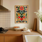 a kitchen counter with a bowl of fruit, a vase of flowers, and a framed print of a colorful floral design hanging on the wall above it.