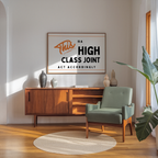 a modern living room with a wooden cabinet, a green armchair, and a framed sign on the wall that reads "This is a HIGH CLASS JOINT ACT ACCORDINGLY".