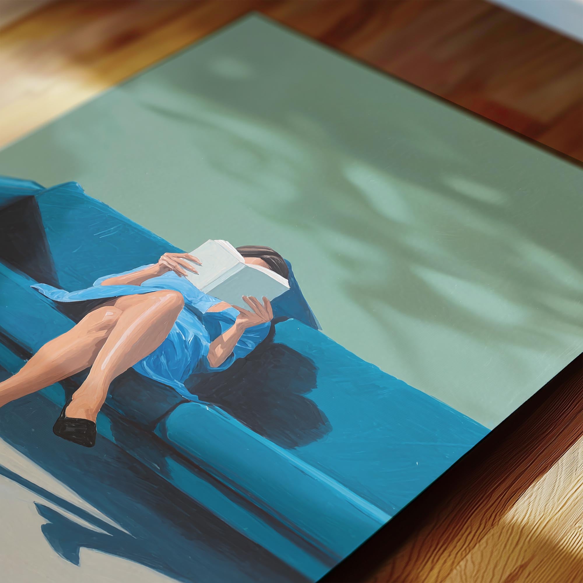A woman is sitting on a blue couch, reading a book.