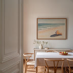 a serene dining room with a white table and chairs, a framed painting of a beach scene, and a vase of flowers on the table.