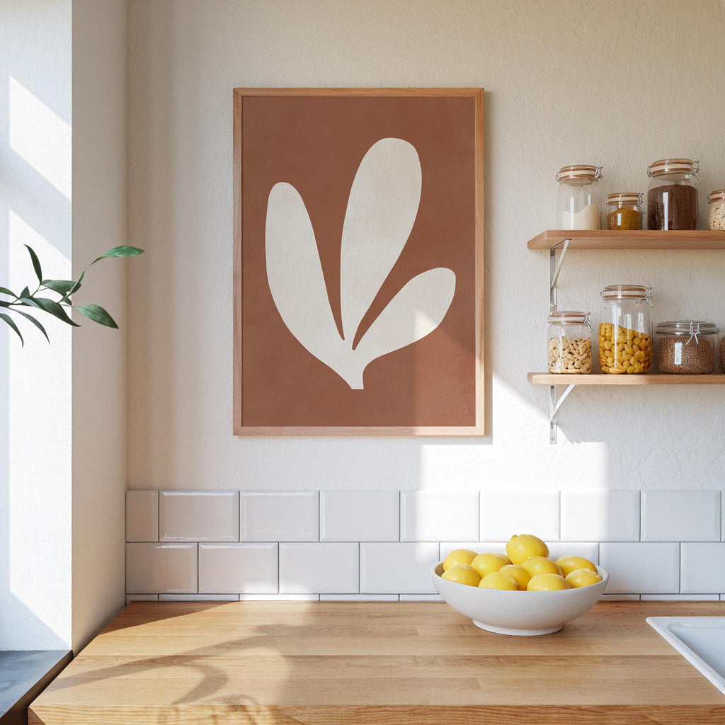 a kitchen counter with a bowl of lemons, a framed plant-like artwork, and shelves displaying various jars and containers.