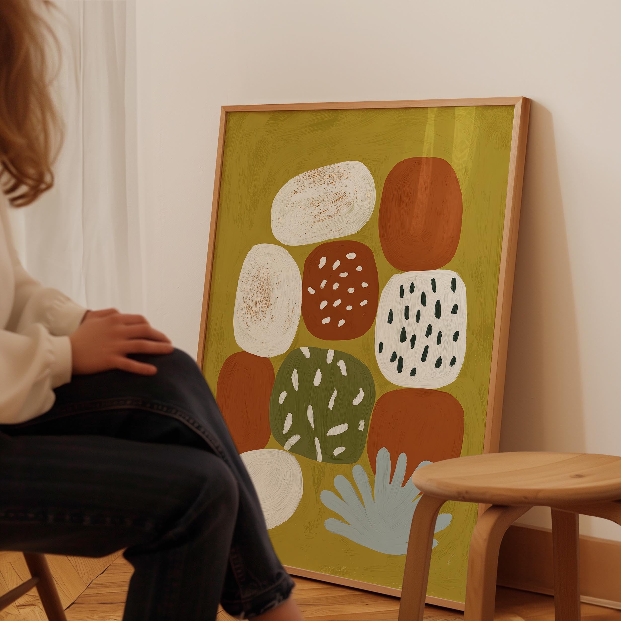 A person is sitting in a chair in front of a large abstract painting on the wall.