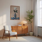 a cozy living room with a white armchair, a wooden sideboard, a potted plant, and a framed painting of a flower on the wall.