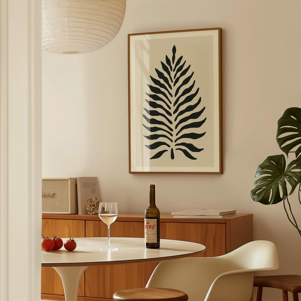 a dining area with a table, a wine bottle, a wine glass, and a framed leaf-like artwork on the wall.