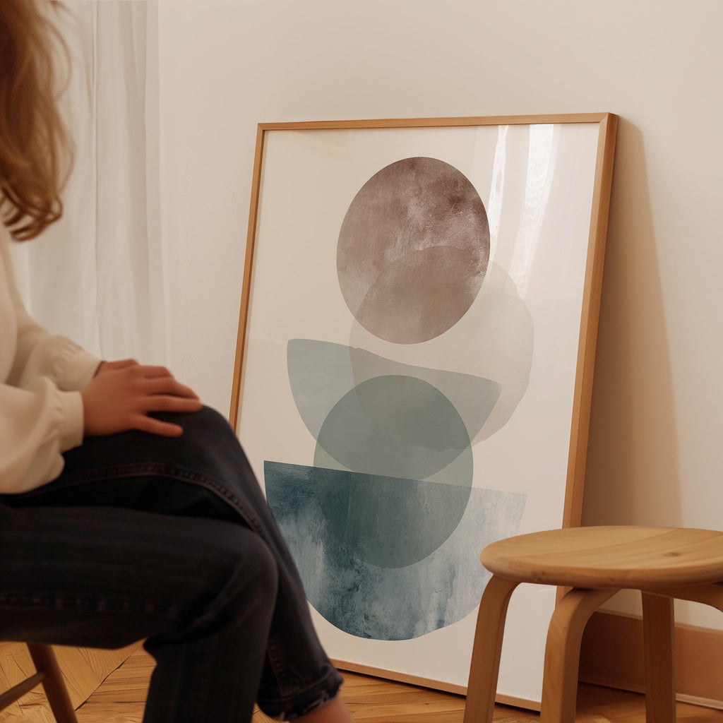 A person is sitting on a stool in front of a large abstract painting on the wall.