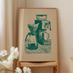 a framed illustration of a coffee maker and a coffee grinder on a table.
