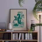 a framed illustration of a coffee maker on a bookshelf, surrounded by various books and decorative items.