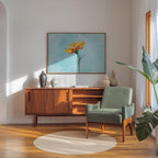 a cozy living room with a wooden sideboard, a green armchair, and a large painting of a yellow flower on the wall.