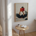 a person sitting on a bed, reading a book, with a cup of coffee and a small table nearby.