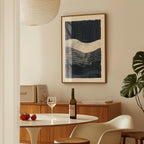 a dining room with a table set for two, a bottle of wine, and a framed abstract painting on the wall.