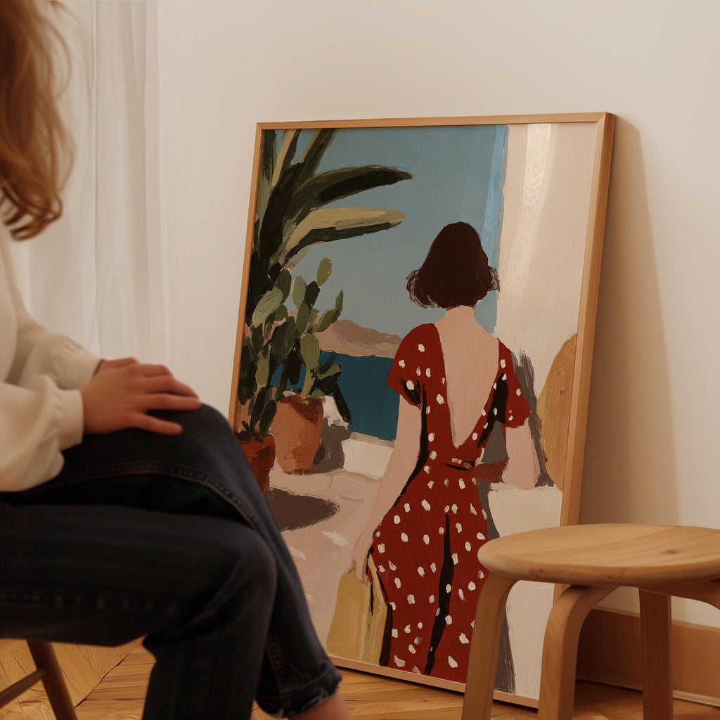 A person is sitting in front of a large painting depicting a woman in a red dress with white polka dots, looking out a window.