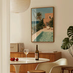 a dining area with a table set for two, a bottle of wine, and a framed painting of a tropical beach scene hanging on the wall.