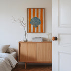 a cozy bedroom scene with a bed, a wooden dresser, and a framed artwork featuring a seashell.