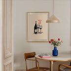 a dining area with a table, chairs, and a framed poster on the wall. The poster has a drawing of wine glasses and a bottle, along with the text "GOSSIP AND WINE".