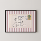 The image is a framed postcard with a handwritten message that reads "it feels so good to be home".