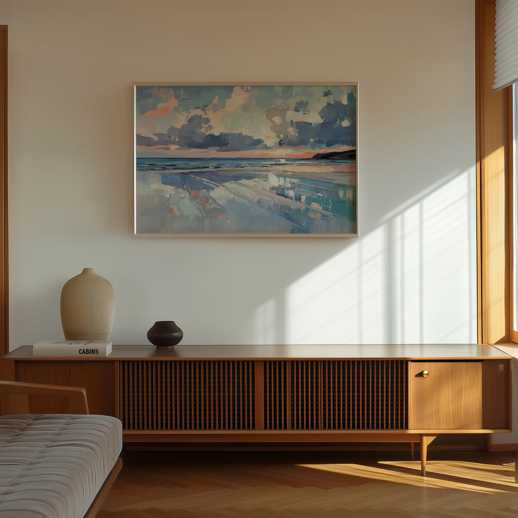 a serene indoor setting with a large painting of a beach scene hanging on the wall above a wooden cabinet or entertainment center. The painting depicts a tranquil beach landscape with a cloudy sky and a calm ocean. The cabinet has a vase and a book on top, adding a touch of personalization to the space. The room is illuminated by natural light coming through a window, creating a warm and inviting atmosphere.