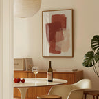 a dining area with a table, a bottle of wine, and a framed abstract painting on the wall.