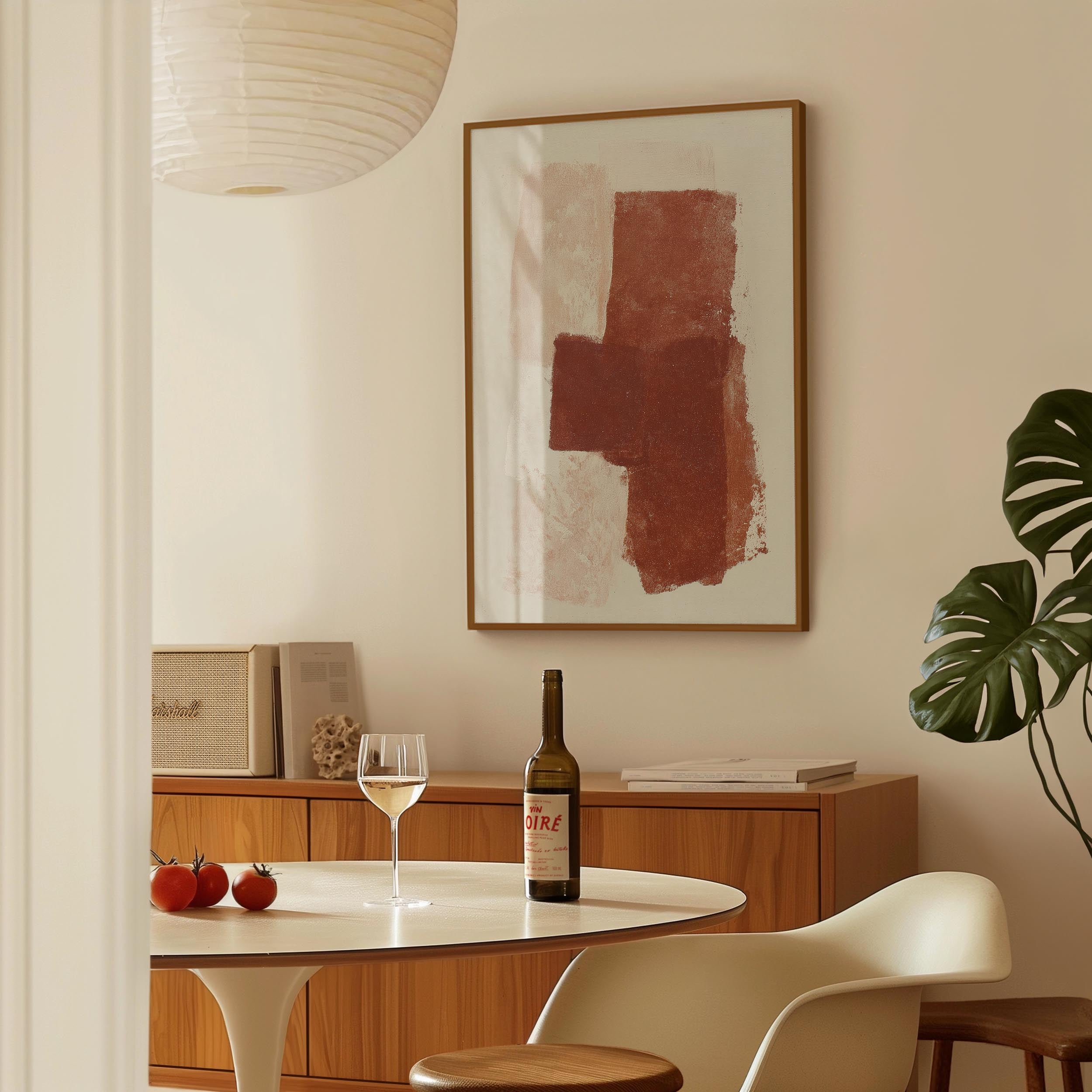 a dining room with a table set for two, a bottle of wine, and a framed abstract painting on the wall.