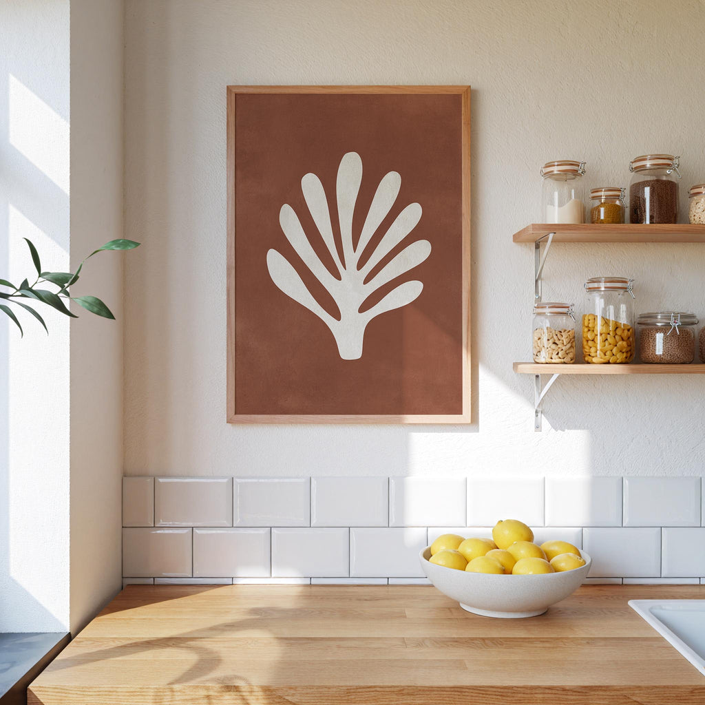 a kitchen counter with a bowl of lemons, a framed plant print, and a shelf with various jars and containers.
