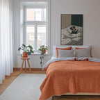 a cozy bedroom with a large bed, a wooden stool with a potted plant, and a framed artwork of a person on a bed. The room has white walls and a large window, creating a bright and airy atmosphere.