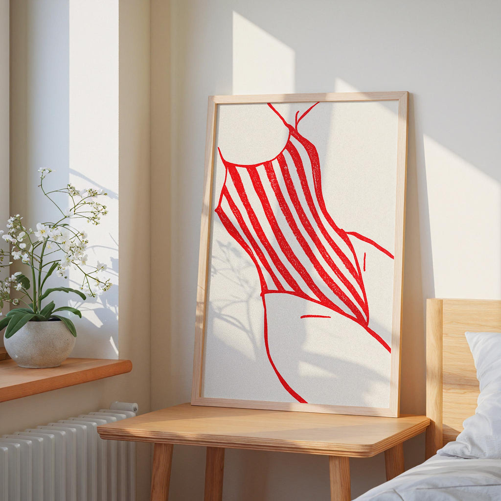 a bedroom scene with a large framed artwork of a red and white striped swimsuit on the wall, a wooden table, and a potted plant.