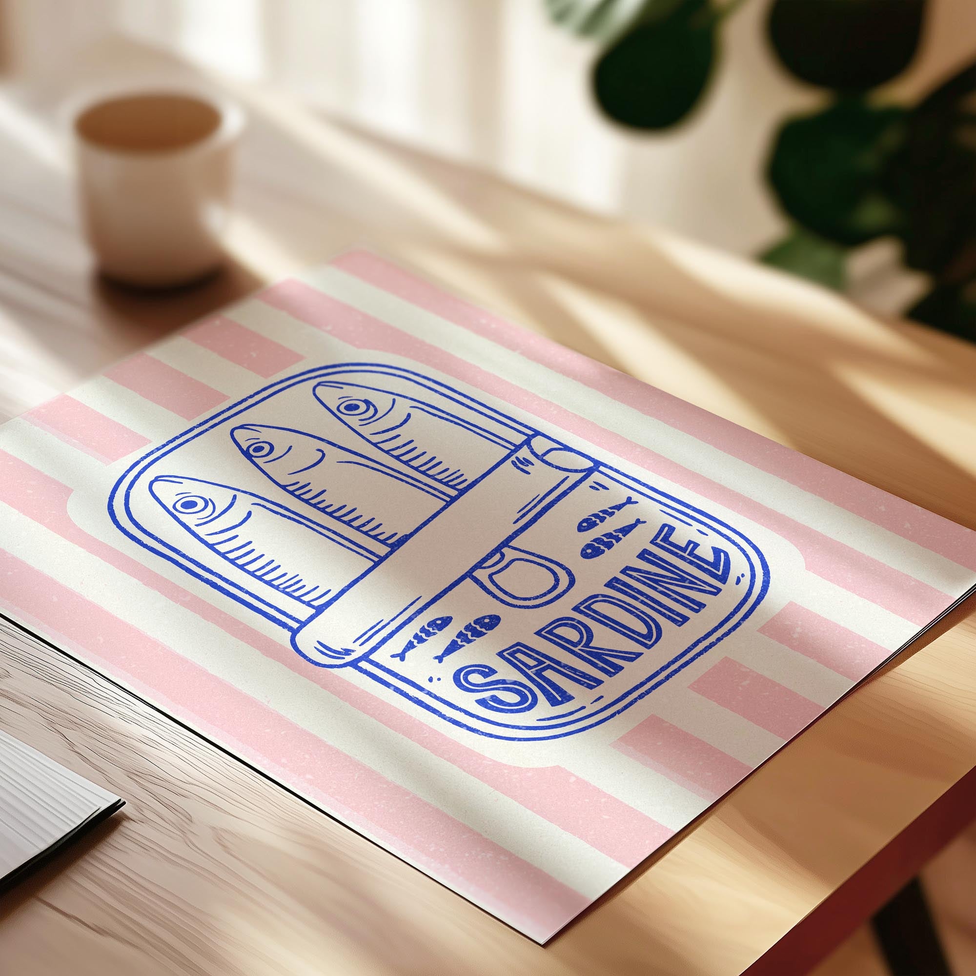 A pink and white striped paper with a blue illustration of a can of sardine on it, placed on a wooden surface.