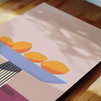 a close-up view of a piece of art that depicts a still life scene with three oranges arranged on a blue surface.
