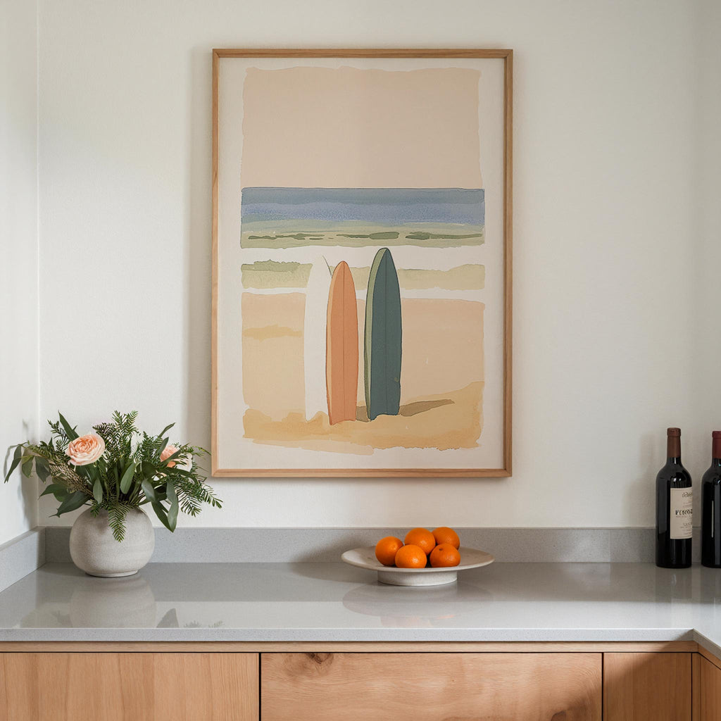 a framed painting of two surfboards on a wall above a counter with a vase of flowers and a plate of oranges.