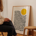 A person is sitting in a chair in front of a large abstract art print on a wall.